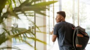 Delivery professional carrying package bag inside modern office building.