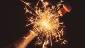 Champagne bottle popping with sparkling celebration fireworks on dark background