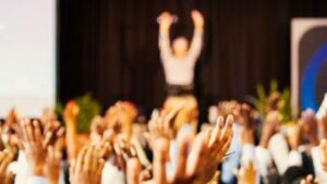 Audience raising hands during live seminar or motivational speaker presentation