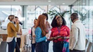 Business professionals networking and conversing in modern office lobby.