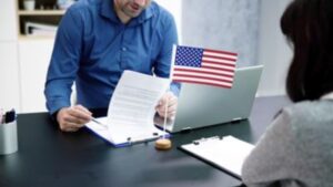 Professional reviewing immigration paperwork with U.S. flag on desk